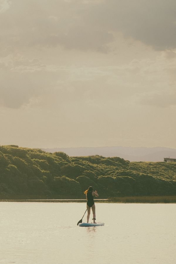 Mujer haciendo paddle surf en una bahía de agua tranquila